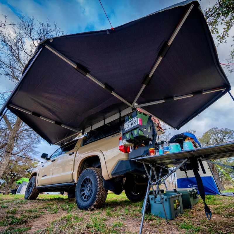 Overland vehicle systems nomadic 270 awning driverside open rear corner view on toyota tacoma in nature camp 800x800